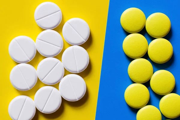 Top view of round shape pills on blue and yellow background — Stock Photo