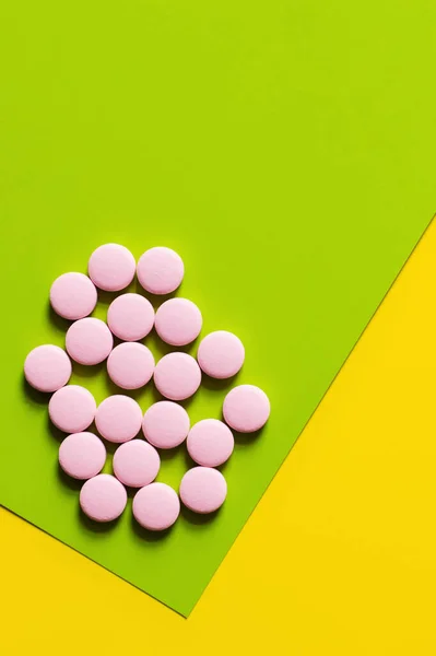 Top view of round shape pink pills on yellow and green background — Foto stock