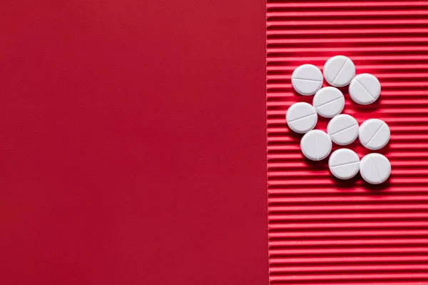 Vue de dessus de pile avec des pilules de forme ronde blanche sur fond texturé cramoisi — Photo de stock