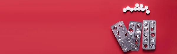 Top view of used blister packs near round shape pills on crimson background, banner — Fotografia de Stock