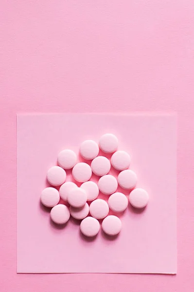 Vista dall'alto di pillole di forma rotonda sulla nota di carta isolata su rosa — Foto stock