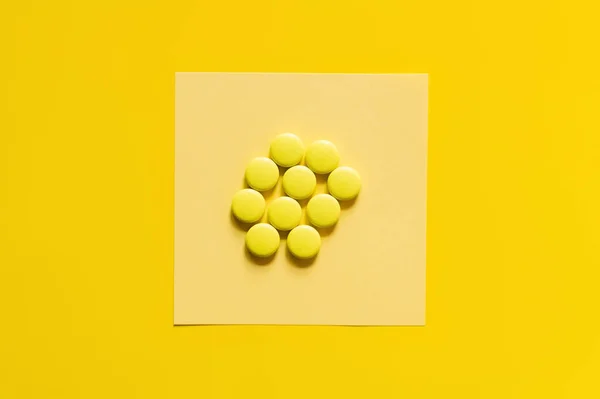 Top view of round shape pills on paper note on yellow — Stock Photo