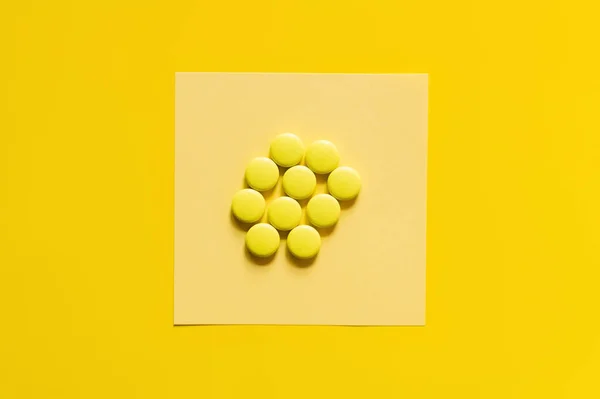 Top view of round shape pills on paper note on yellow — стоковое фото