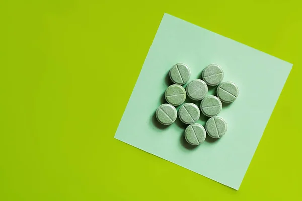 Top view of round shape pills on paper note on green — Stock Photo