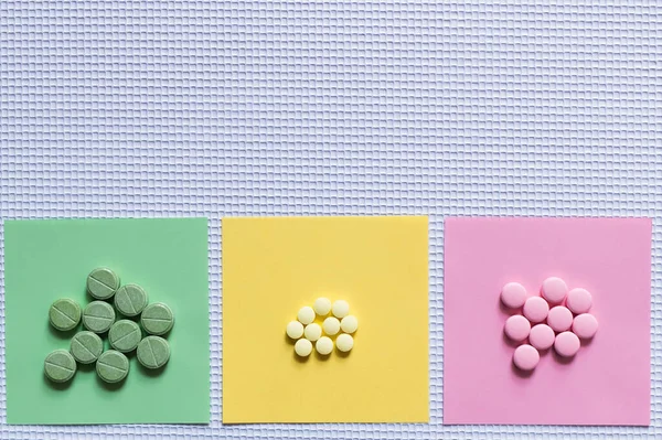 Top view of colorful round shape pills on paper notes on textured white background - foto de stock