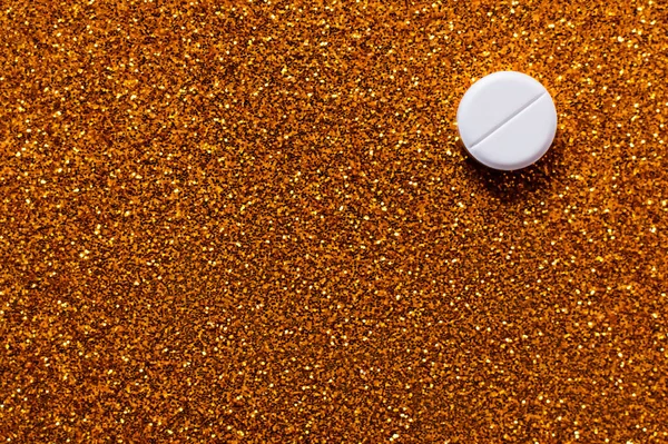 Top view of white pill on shiny brown gold background — Stock Photo