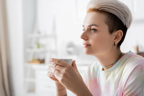 Young and stylish woman holding cup of coffee at home — Stockfoto