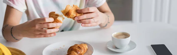 Partial view of woman holding delicious croissant near coffee cup, banner — Photo de stock
