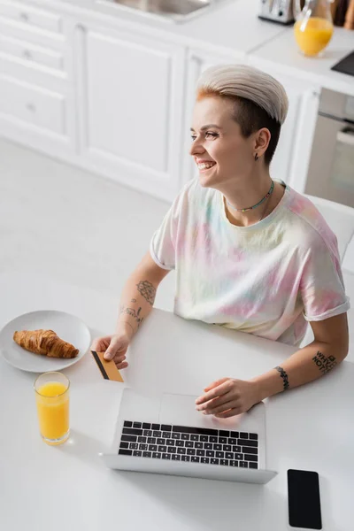 Happy woman with credit card near laptop, orange juice and croissant — Photo de stock