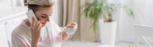 Mujer joven con taza de café hablando en el teléfono inteligente por la mañana, pancarta - foto de stock