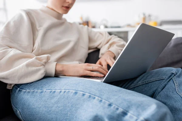 Cropped view of woman typing on laptop on blurred background — Stockfoto