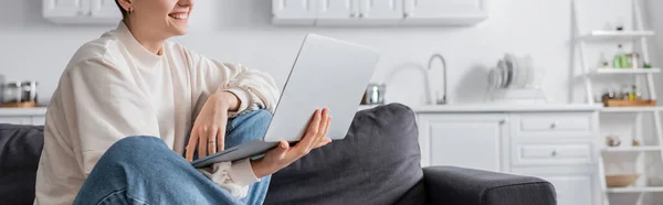 Partial view of cheerful woman sitting with laptop at home, banner — Stock Photo