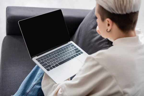 Mujer borrosa sosteniendo portátil con pantalla en blanco y el hogar — Stock Photo