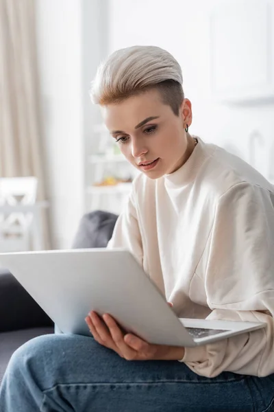 Junge und stilvolle Frau schaut zu Hause auf Laptop — Stockfoto