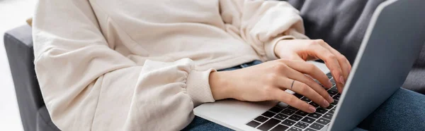 Partial view of woman in white pullover typing on laptop at home, banner — Photo de stock