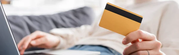 Cropped view of blurred woman holding credit card near laptop, banner — Stockfoto