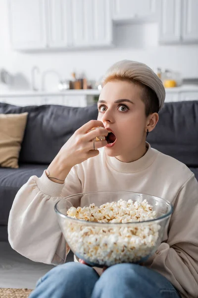 Erstaunte Frau schaut fern und isst zu Hause Popcorn — Stockfoto