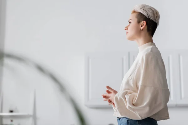 Side view of pensive woman with trendy hairstyle looking away at home — стоковое фото