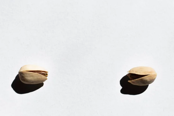 Flat lay of two cracked pistachios on white background — Stockfoto