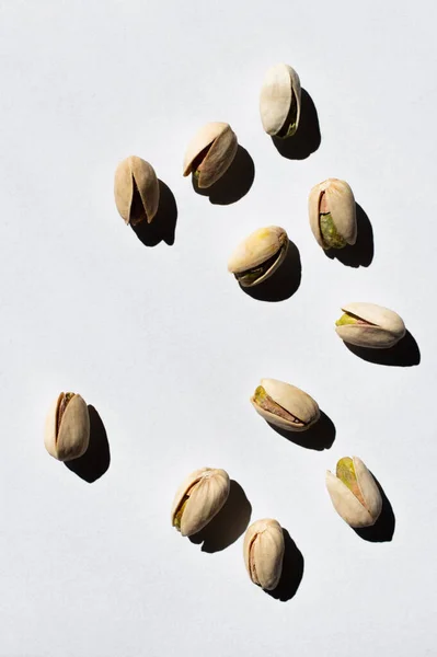 Top view of cracked green and salty pistachios on white background — Photo de stock