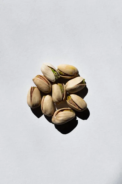 Top view of pile with cracked green and salty pistachios on white background — Stockfoto