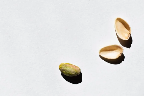 Top view of cracked green and salty pistachio on white background — Stockfoto