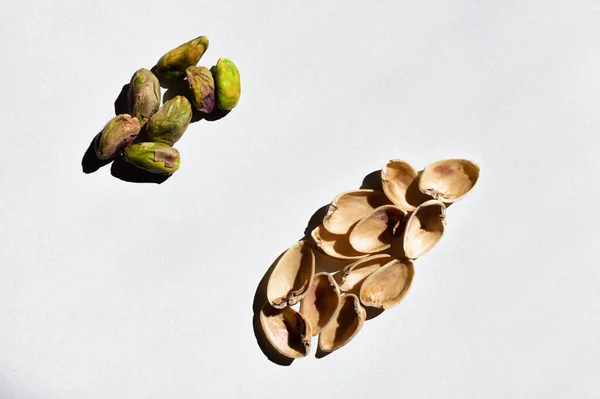 Top view of organic and salty pistachios near nutshells on white background — Stockfoto