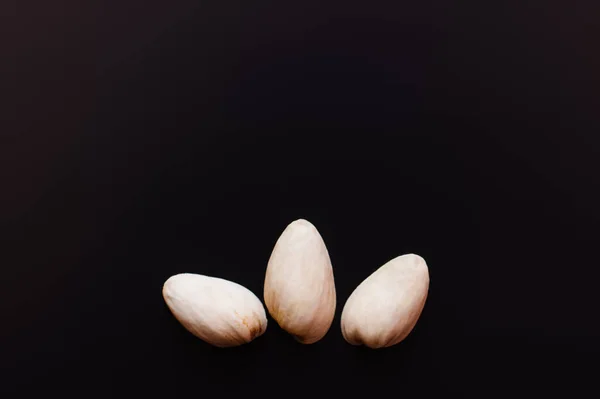 Vista superior de pistachos en cáscaras de nuez aisladas en negro - foto de stock