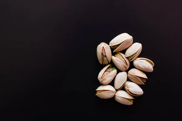 Top view of cracked and salty pistachios isolated on black — стоковое фото