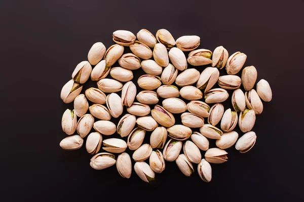 Top view of pile with salty pistachios isolated on black - foto de stock