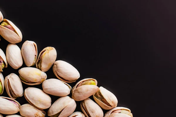 Top view of tasty and salty pistachios isolated on black — стоковое фото