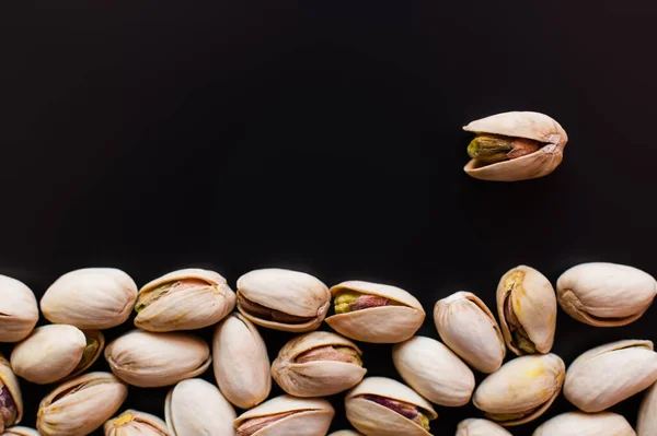 Top view of tasty and natural pistachios with salt isolated on black — Fotografia de Stock