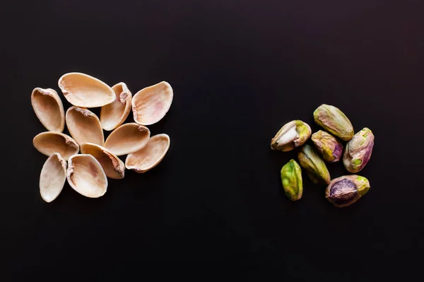 Top view of nutshells near pistachios isolated on black — Foto stock