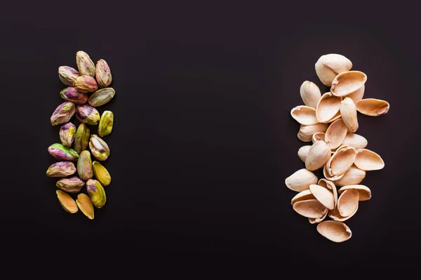 Top view of nutshells near tasty pistachios isolated on black — стоковое фото