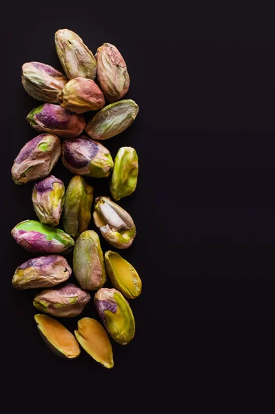 Top view of green and salty pistachios without shell isolated on black — Stock Photo