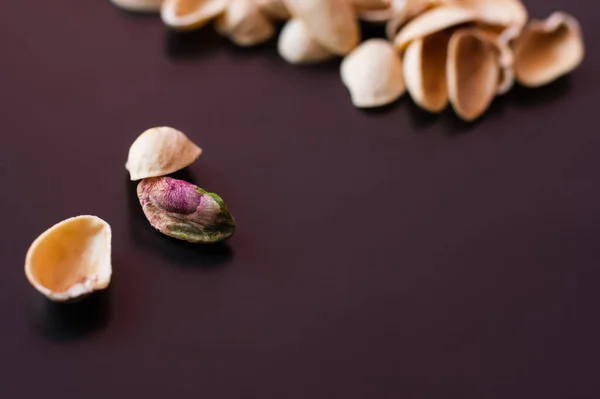 Close up view of pistachio near blurred nutshells on black — стоковое фото