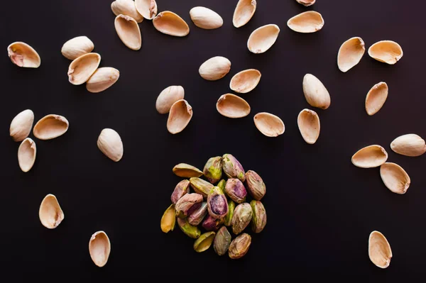 Top view of nutshells and salty pistachios isolated on black — Fotografia de Stock