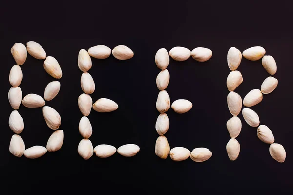 Top view of beer word made of pistachio nutshells isolated on black — Stock Photo
