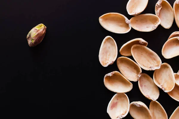 Top view of nutshells and tasty pistachio nut isolated on black — Stockfoto