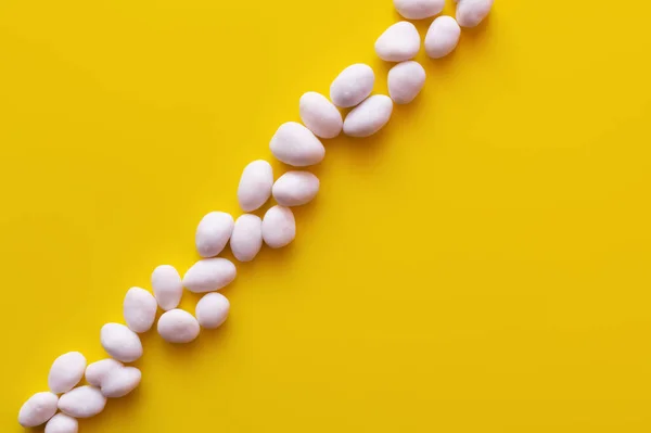 Top view of row with peeled pine nuts on yellow background - foto de stock