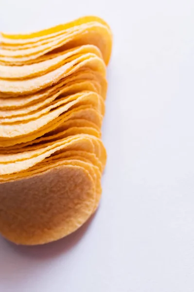 Закрыть вид на соленые и хрустящие картофельные чипсы на белом — стоковое фото