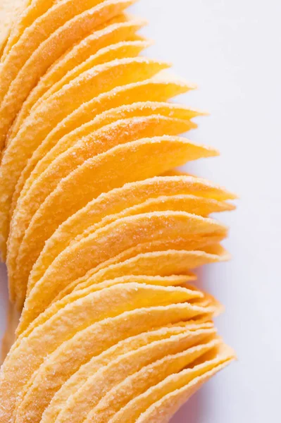 Close up of salty and fried potato chips on white — Stock Photo