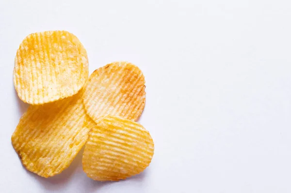 Vista superior de batatas fritas onduladas e salgadas em branco — Fotografia de Stock