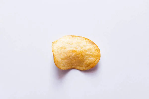 Top view of single fried and salty potato chip on white - foto de stock