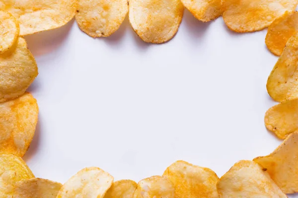 Flat lay view of delicious, fried and salty potato chips on white — Fotografia de Stock