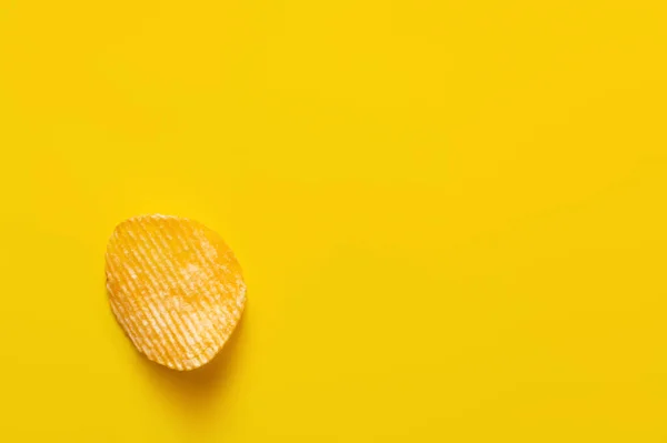 Draufsicht auf einzelne wellige und salzige Kartoffelchips auf gelb — Stockfoto