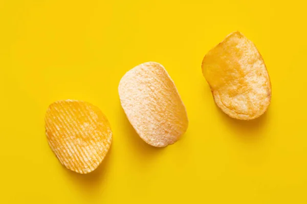 Top view of different salty potato chips on yellow — Photo de stock