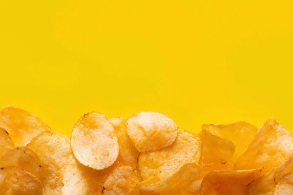 Top view of delicious, crunchy and salty potato chips on yellow with copy space — стоковое фото