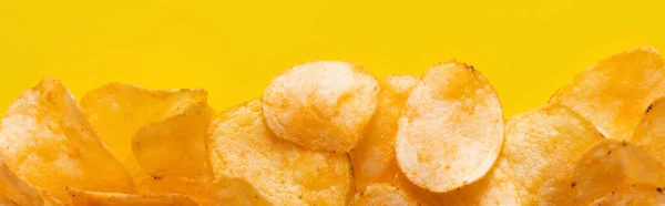 Blick von oben auf leckere, knusprige und salzige Kartoffelchips auf gelb, Banner — Stockfoto