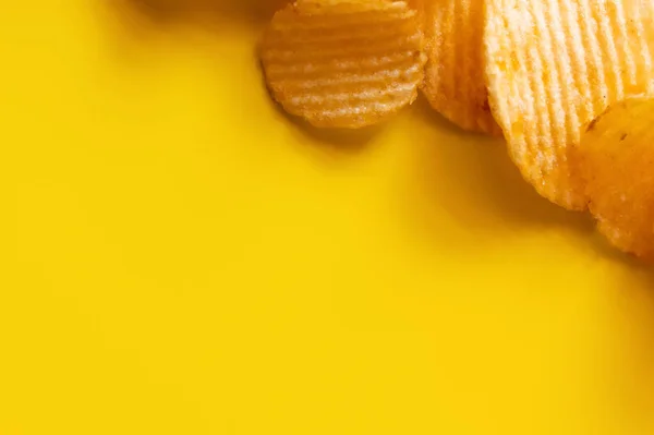 Vista superior de batatas fritas onduladas e salgadas no amarelo — Fotografia de Stock